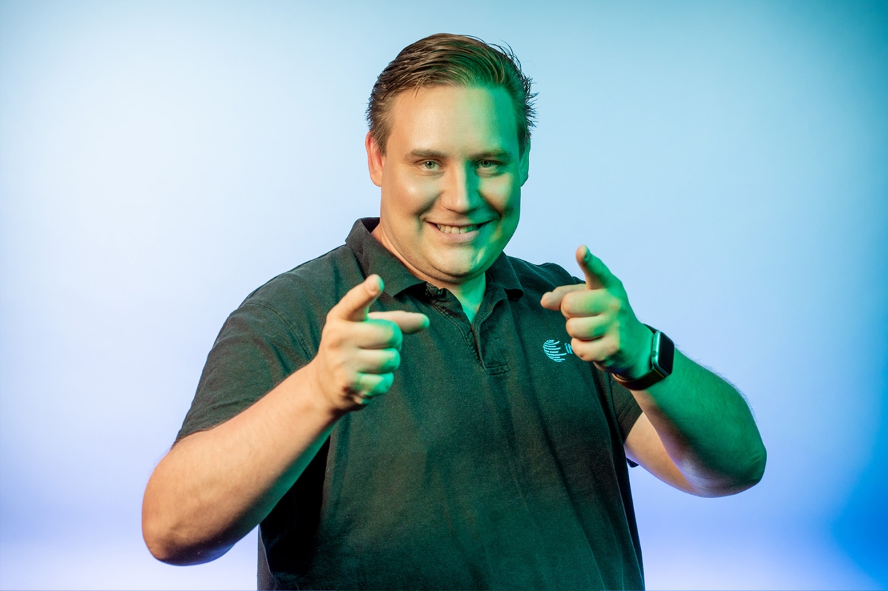 Mann der lächelt und mit beiden Zeigefingern in die Kamera zeigt