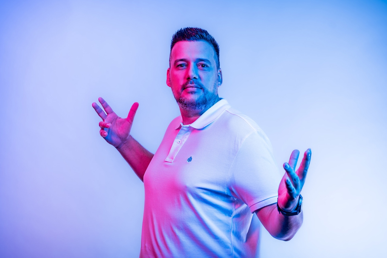 Mann guckt in die Kamera und hat beide Arme offen