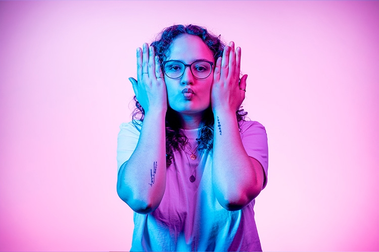 Frau macht einen Fischmund und hält sich die Hände neben das Gesicht